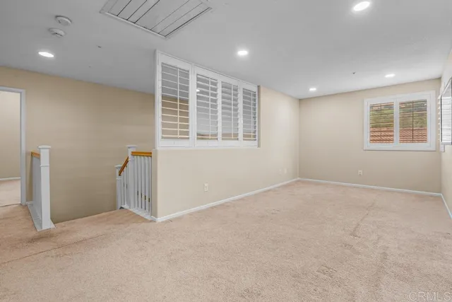 a view of an empty room with a window and a kitchen