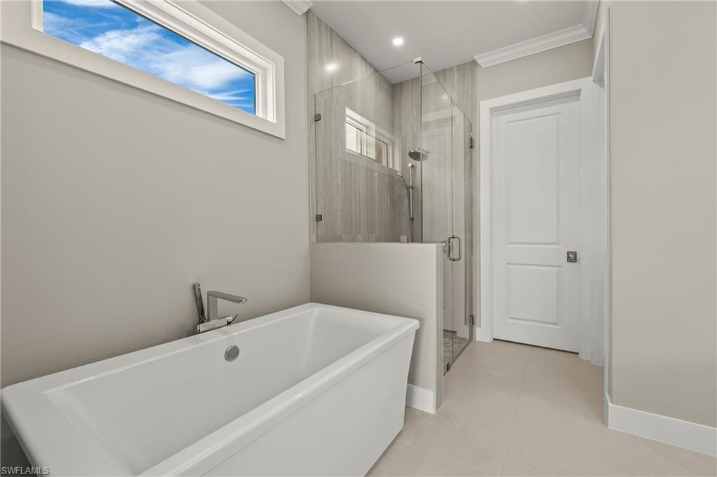 1134 Trail Terrace Drive Naples, FL 34103 - Photo 21 of 37 Bathroom with a stall shower, baseboards, a freestanding bath, and crown molding