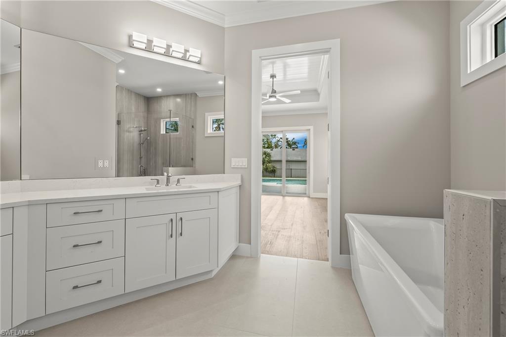 1134 Trail Terrace Drive Naples, FL 34103 - Photo 22 of 37 Full bath featuring a soaking tub, crown molding, vanity, a ceiling fan, and a stall shower