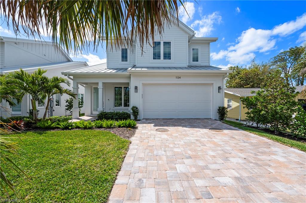 1134 Trail Terrace Drive Naples, FL 34103 - Photo 3 of 37 View of front of house featuring a front yard, a standing seam roof, an attached garage, metal roof, and decorative driveway