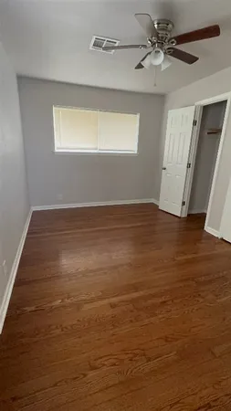 a view of an empty room with window and wooden floor