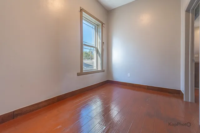 a view of an empty room with wooden floor and closet