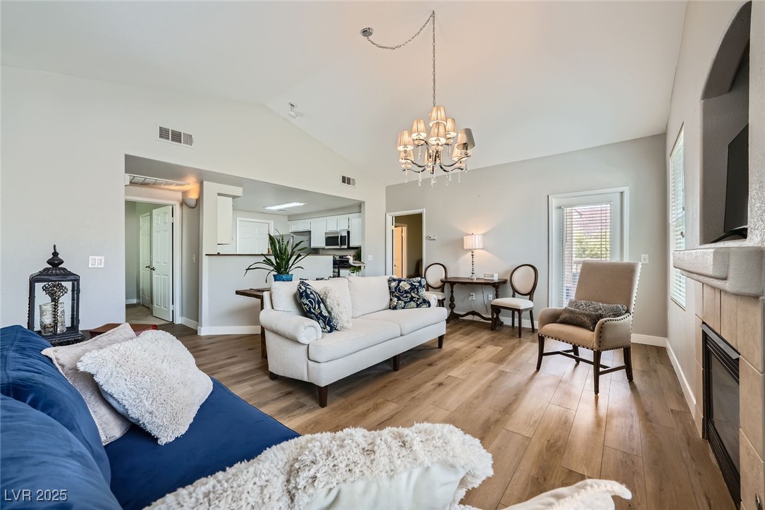10550 West Alexander Road, Unit 2179 Las Vegas, NV 89129 - Photo 1 of 28 Living area featuring vaulted ceiling, a notable chandelier, light wood-style floors, and visible vents
