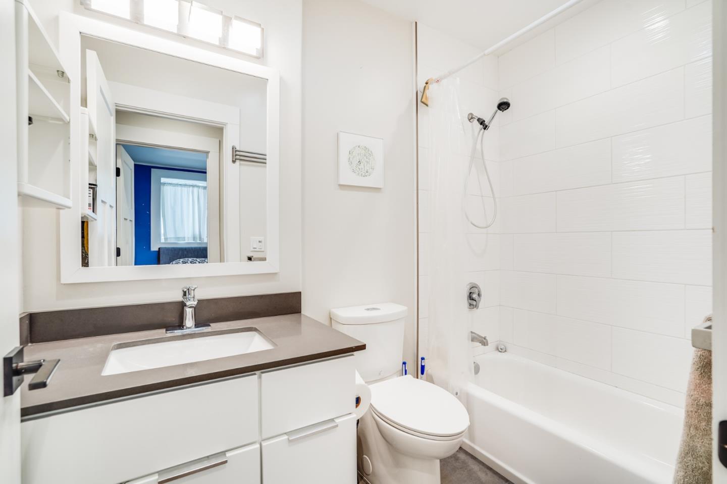 985 44th Street Oakland, CA 94608 - Photo 32 of 41 a bathroom with a granite countertop sink a toilet and shower