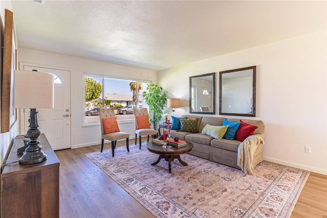 7738 Encinitas Avenue Fontana, CA 92336 - Photo 8 of 35 a living room with furniture a rug and a large mirror next to a window