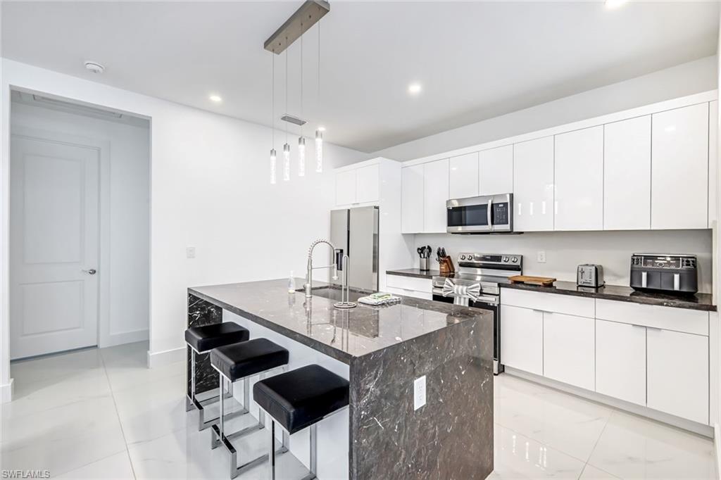 502 Southwest 25th Place Cape Coral, FL 33991 - Photo 24 of 34 a kitchen with stainless steel appliances granite countertop a sink a stove a refrigerator cabinets and chairs
