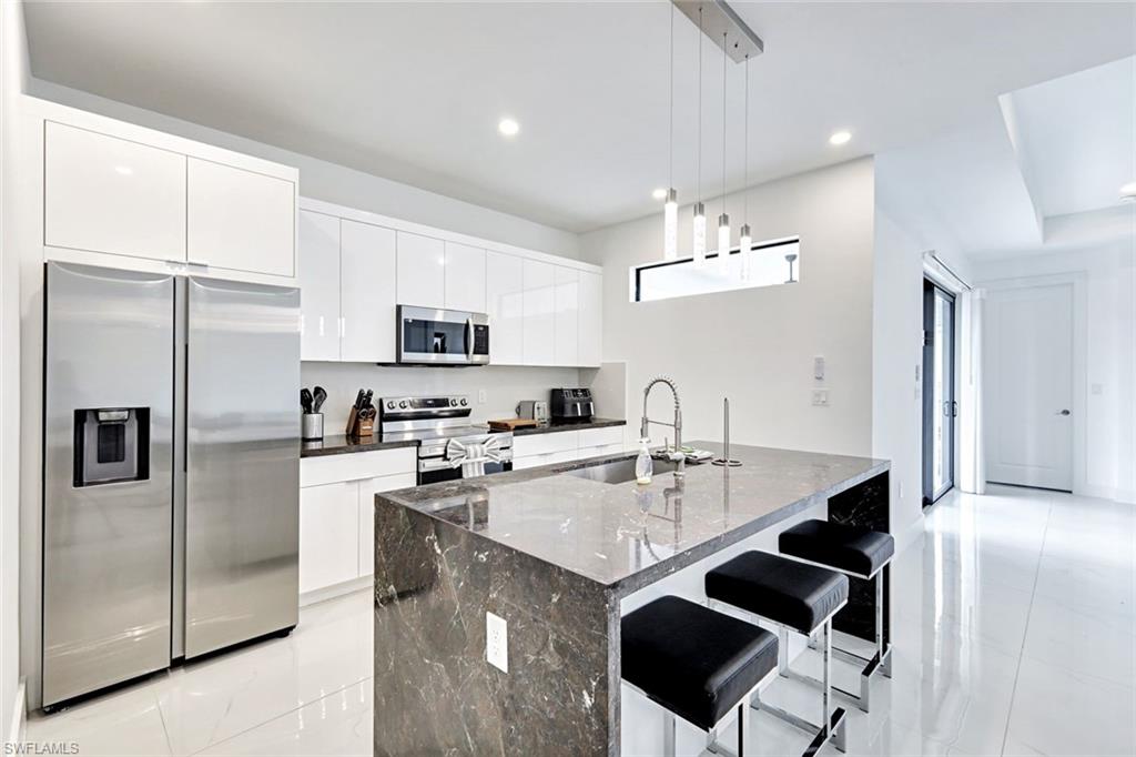 502 Southwest 25th Place Cape Coral, FL 33991 - Photo 25 of 34 a kitchen with stainless steel appliances granite countertop a sink a stove a refrigerator cabinets and a dining table