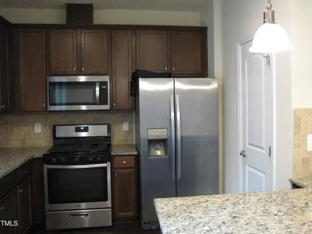 a kitchen with granite countertop wooden cabinets and stainless steel appliances