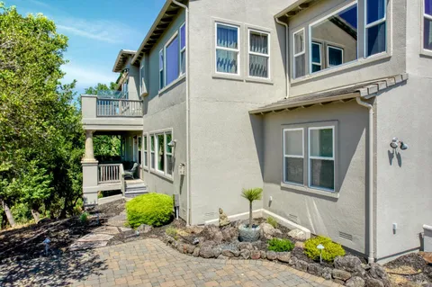 a view of a white house with large windows plants and large trees