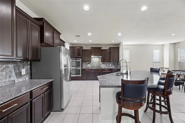 a kitchen with stainless steel appliances a dining table chairs refrigerator and sink