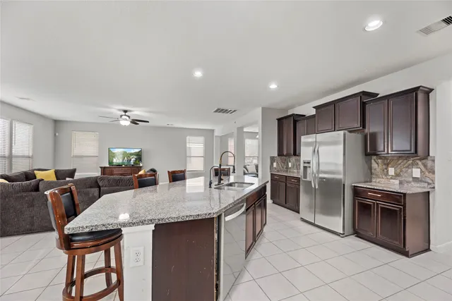 a kitchen with stainless steel appliances kitchen island granite countertop a refrigerator a stove a sink dishwasher with a dining table and chairs
