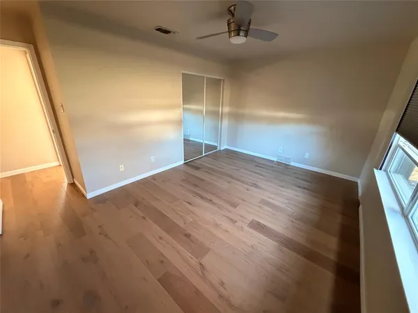 en empty room with wooden floor and windows