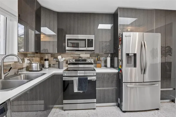 a kitchen with stainless steel appliances granite countertop a refrigerator a stove a sink and a microwave