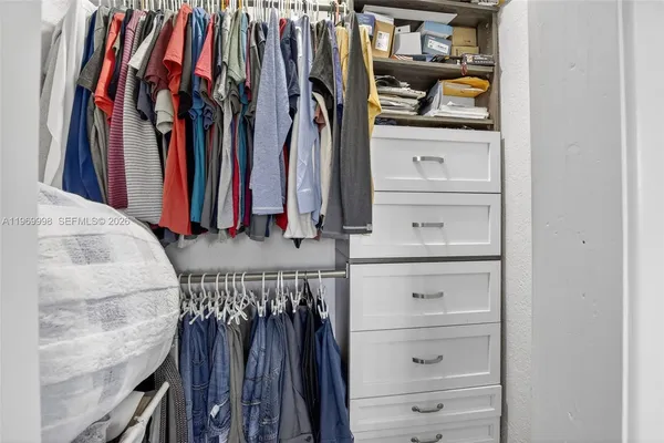 a view of walk in closet with clothes and shoes