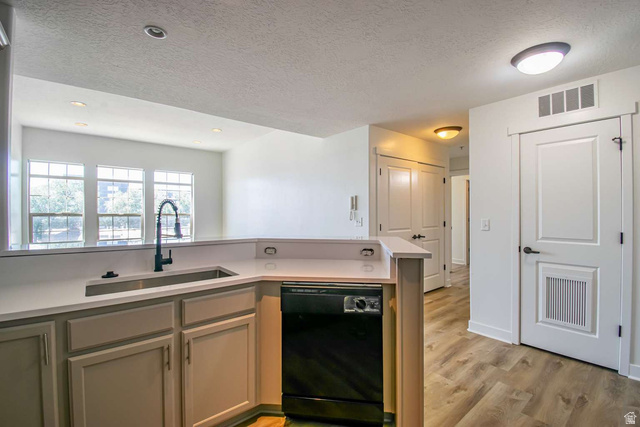 4276 South Main Street, Unit 303 Murray, UT 84107 - Photo 5 of 20 Kitchen peninsula featuring a stainless steel sink with a matte black faucet, light-toned cabinetry, and a black dishwasher