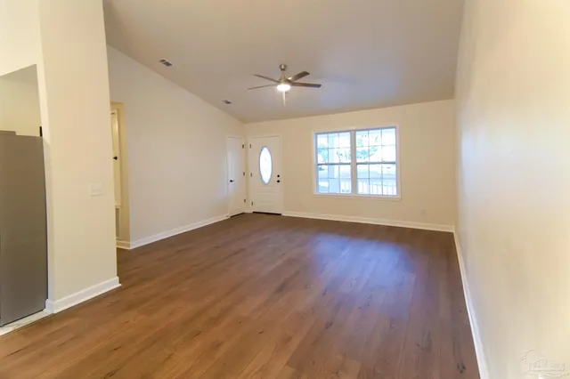 an empty room with wooden floor and windows