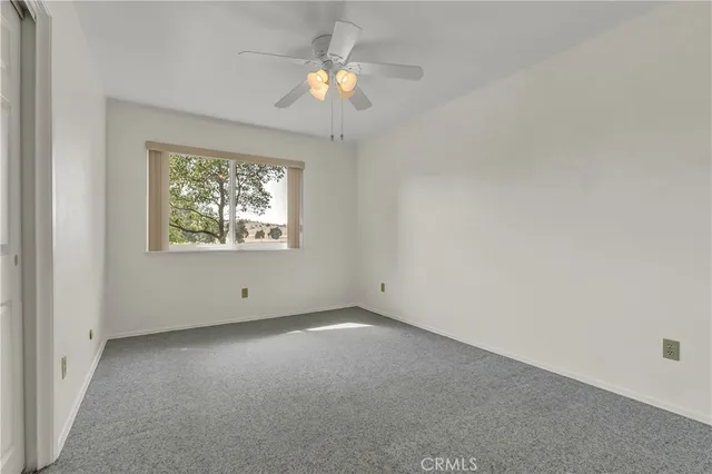 an empty room with windows and fan