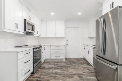 a kitchen with stainless steel appliances white cabinets and a stove top oven