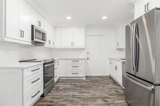 a kitchen with stainless steel appliances white cabinets and a stove top oven