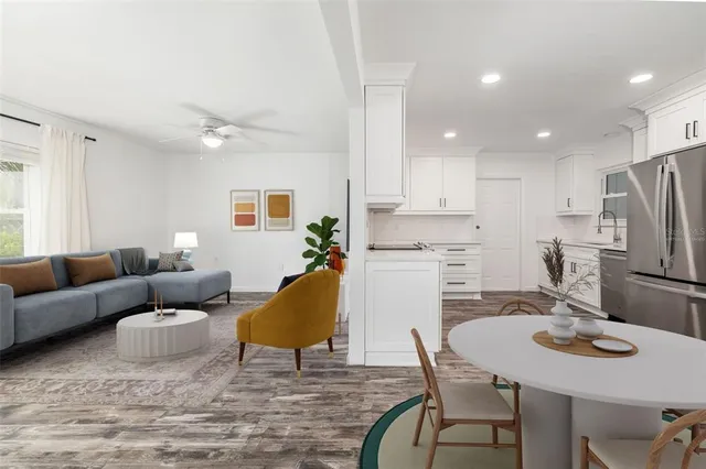 a living room with stainless steel appliances furniture a dining table and kitchen view