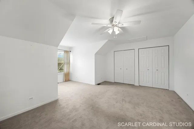a view of an empty room with window and chandelier fan