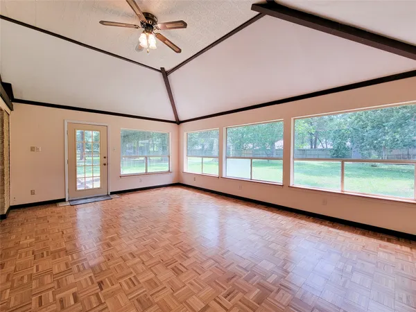 a view of an empty room with a window and wooden floor