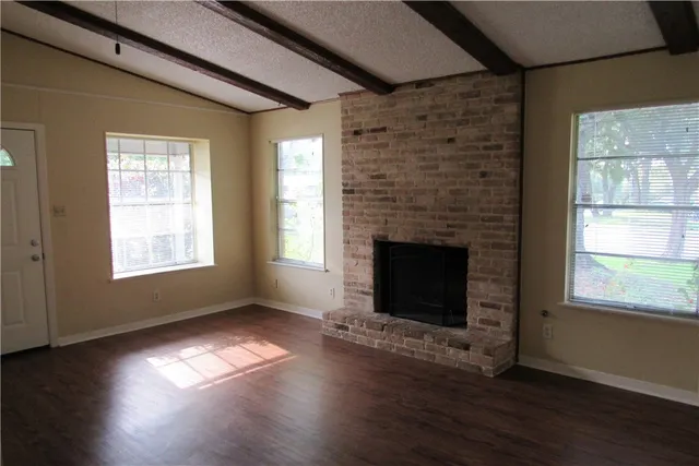 a view of empty room with wooden floor and fireplace