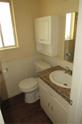 a bathroom with a granite countertop toilet a sink a mirror and a window
