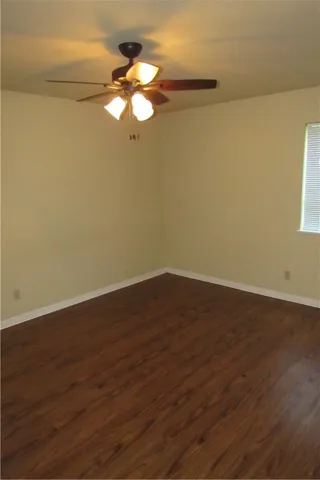 a view of a room with wooden floor and a ceiling fan