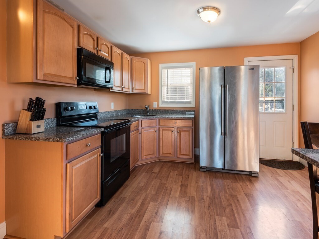 75 Lawrence Street Northborough, MA 01532 - Photo 18 of 38 a kitchen with stainless steel appliances granite countertop wooden floors and white cabinets