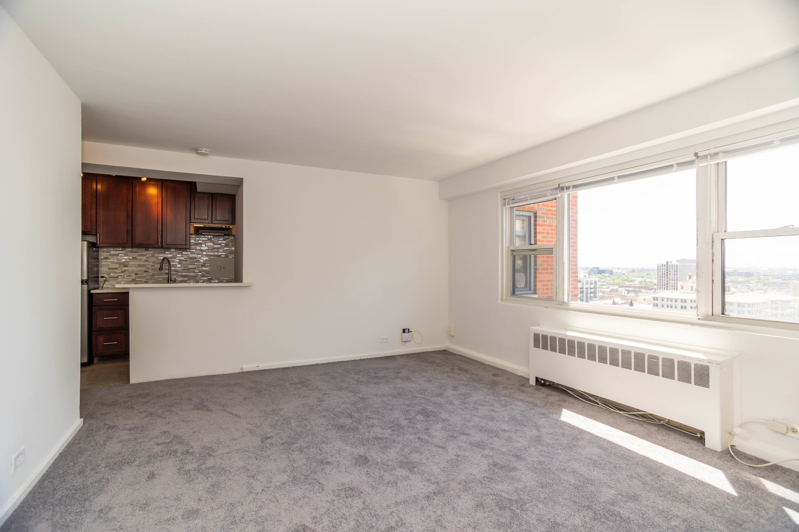 2909 North Sheridan Road, Unit 1701 Chicago, IL 60657 - Photo 10 of 16 a view of an empty room with a window and a kitchen area