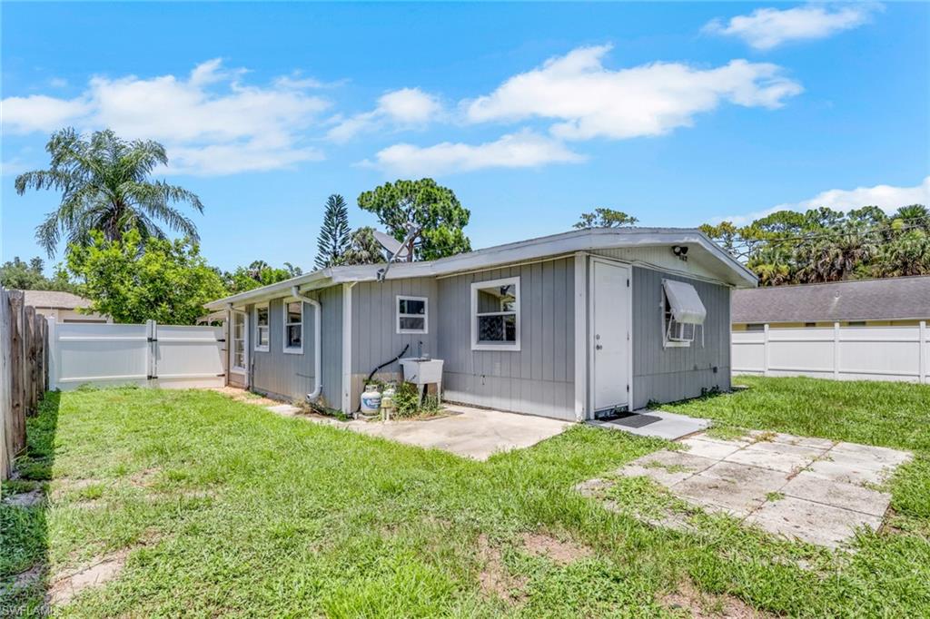 11360 Hunting Road Bonita Springs, FL 34135 - Photo 24 of 27 Expansive backyard featuring a white vinyl privacy fence, concrete patio areas, and a rear structure with horizontal siding