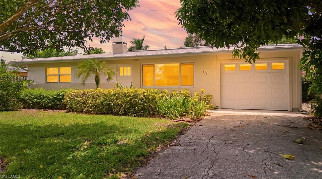 Ranch-style residence featuring a light-toned exterior and a white garage door with window inserts