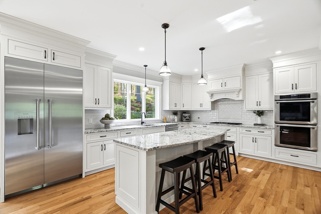 6 Flintlock Road Lexington, MA 02420 - Photo 8 of 39 a kitchen with stainless steel appliances granite countertop a stove a sink a microwave a refrigerator and white cabinets with wooden floor