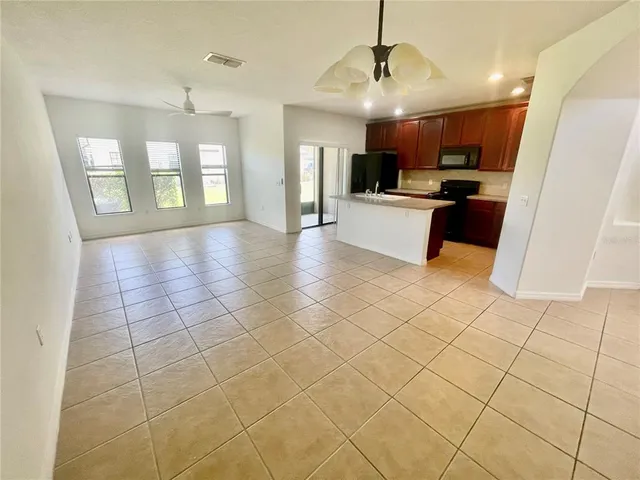 a view of a kitchen with kitchen island granite countertop a refrigerator and a stove top oven