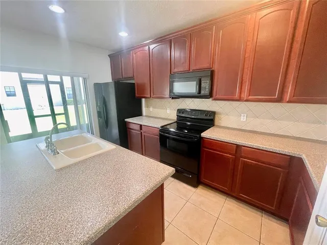 a kitchen with stainless steel appliances granite countertop a refrigerator sink stove microwave and cabinets