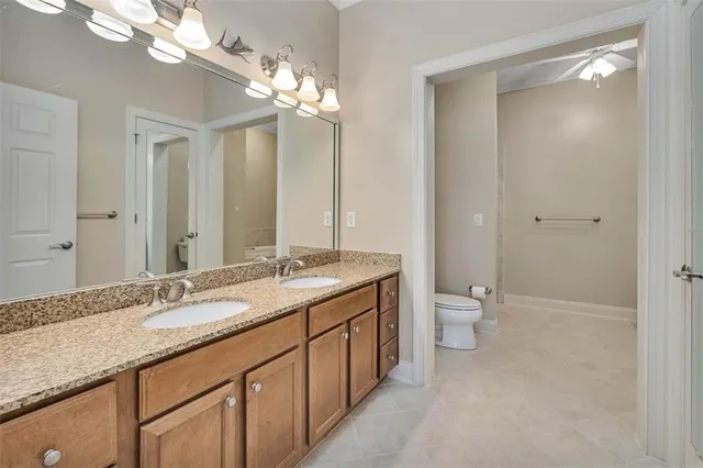 a bathroom with a granite countertop sink a toilet and a large mirror