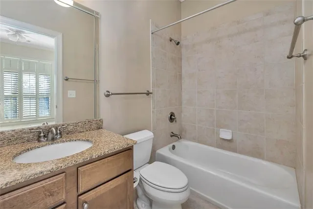 a bathroom with a granite countertop sink toilet mirror and bathtub