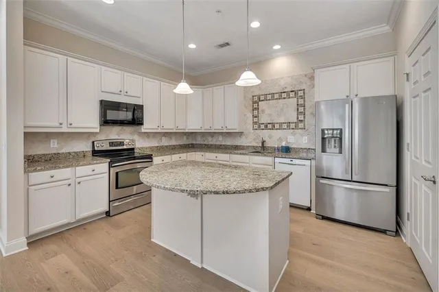 a kitchen with granite countertop a refrigerator stove top oven and sink