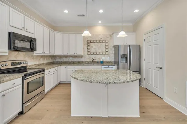 a kitchen with stainless steel appliances granite countertop a sink a stove a refrigerator and cabinets
