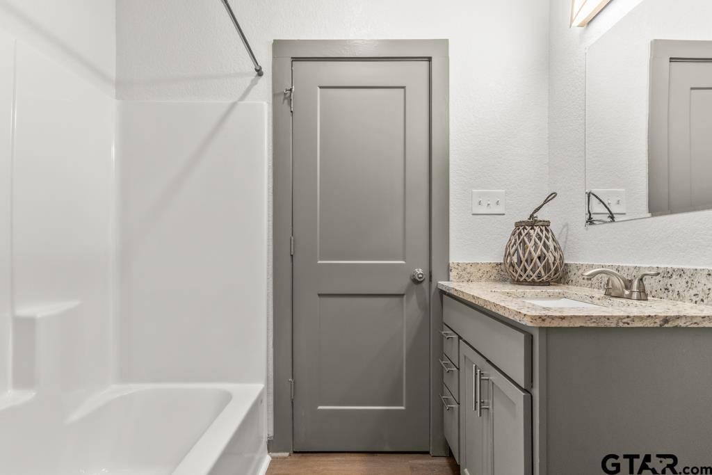 1919 West Jackson Street Tyler, TX 75701 - Photo 26 of 35 a bathroom with a granite countertop sink and a bathtub