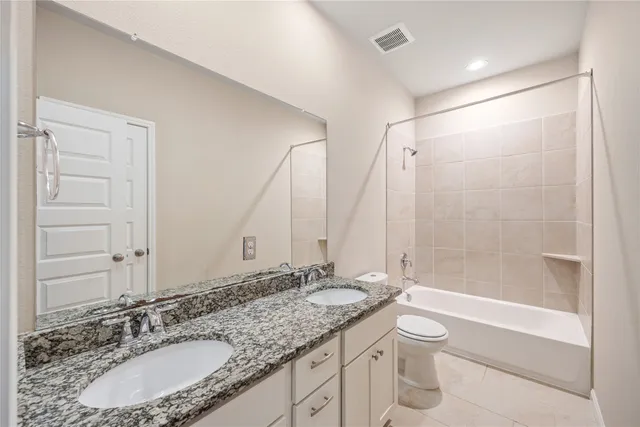 a bathroom with a granite countertop sink a toilet a mirror and shower