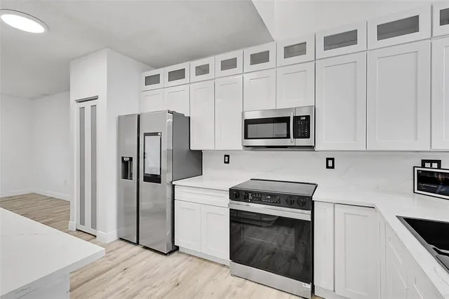 a kitchen with stainless steel appliances white cabinets and wooden floor