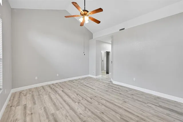 a view of an empty room with window and a ceiling fan