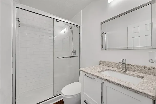 a bathroom with a granite countertop sink toilet and shower