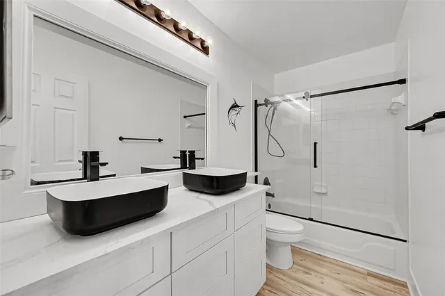 a bathroom with a double vanity sink toilet mirror and shower