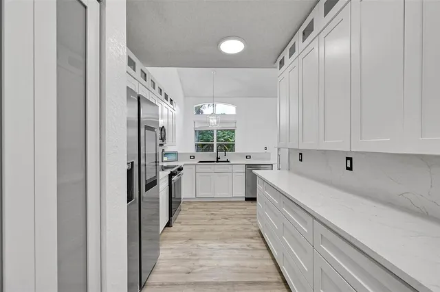 a large white kitchen with sink and stainless steel appliances