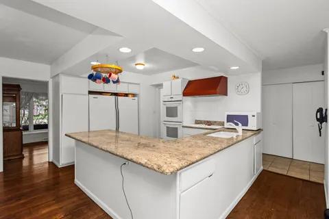 a kitchen with granite countertop kitchen island a sink stove and wooden floor