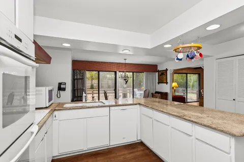 a large white kitchen with a large window a sink and cabinets
