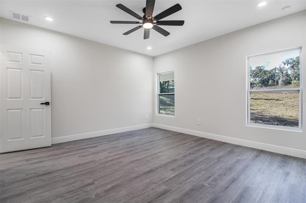 406 Ruby Avenue Deland, FL 32724 - Photo 12 of 23 an empty room with wooden floor chandelier fan and windows